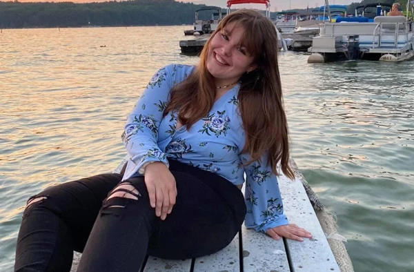 A young woman sitting on the edge of a boat dock.